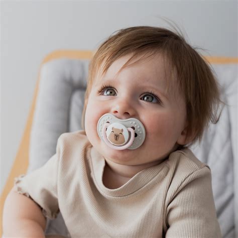 Staršie dieťa podáva cumlík plačúcemu bábätku.