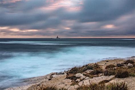 maľba majáku na pobreží s teplým svetlom vyžarujúcim z okien