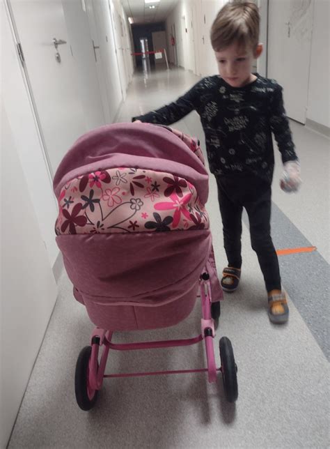 Dieťa sa hrá s bábikou a kočíkom doma